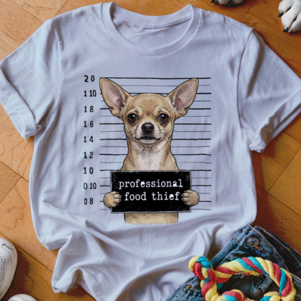 Chihuahua mugshot with "professional food thief" sign on a white t-shirt.