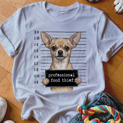 Chihuahua mugshot with "professional food thief" sign on a white t-shirt.
