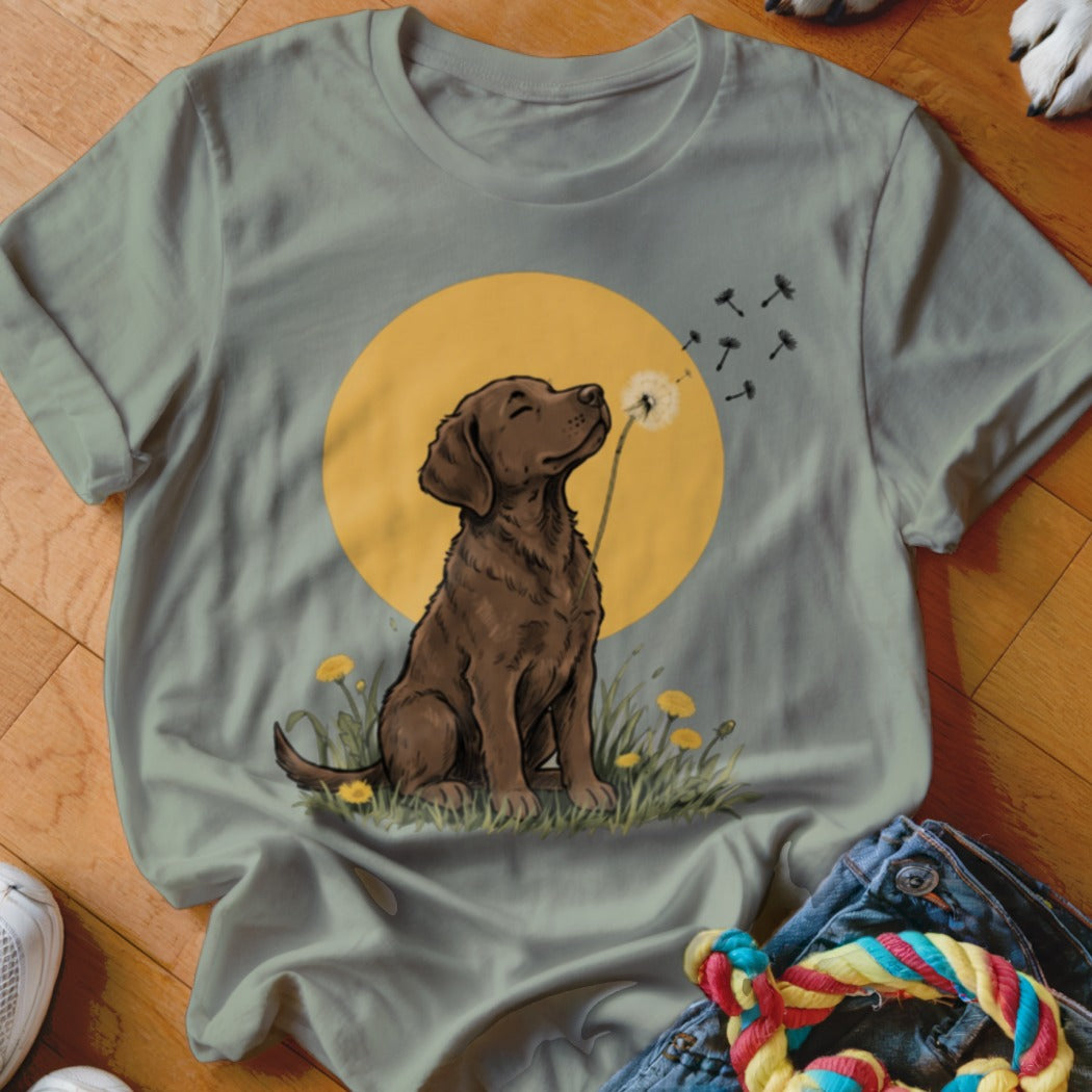 Olive green t-shirt featuring an illustration of a brown dog sniffing a dandelion against a yellow circle background.