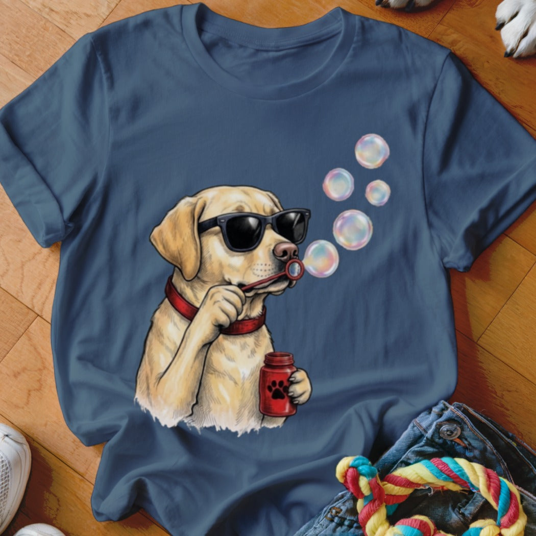 A blue t-shirt printed with a graphic of a yellow lab wearing sunglasses and blowing soap bubbles.