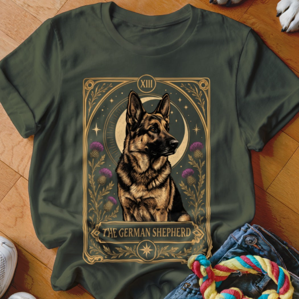 Dark green t-shirt featuring a tarot card graphic of a German Shepherd surrounded by thistles and a moon.