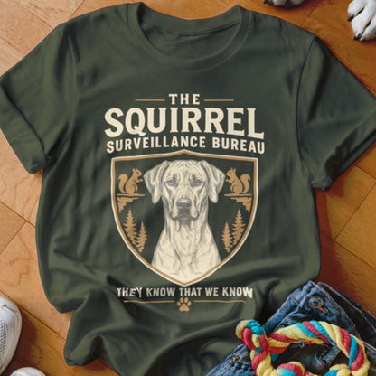 A dark green t-shirt with text that reads The Squirrel Surveillance Bureau and an illustration of a dog inside a crest.