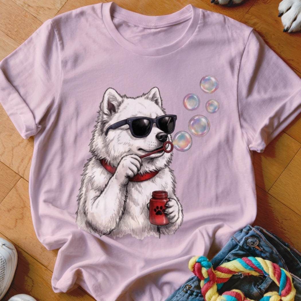 A light pink t-shirt features a graphic of a white dog wearing sunglasses blowing bubbles.
