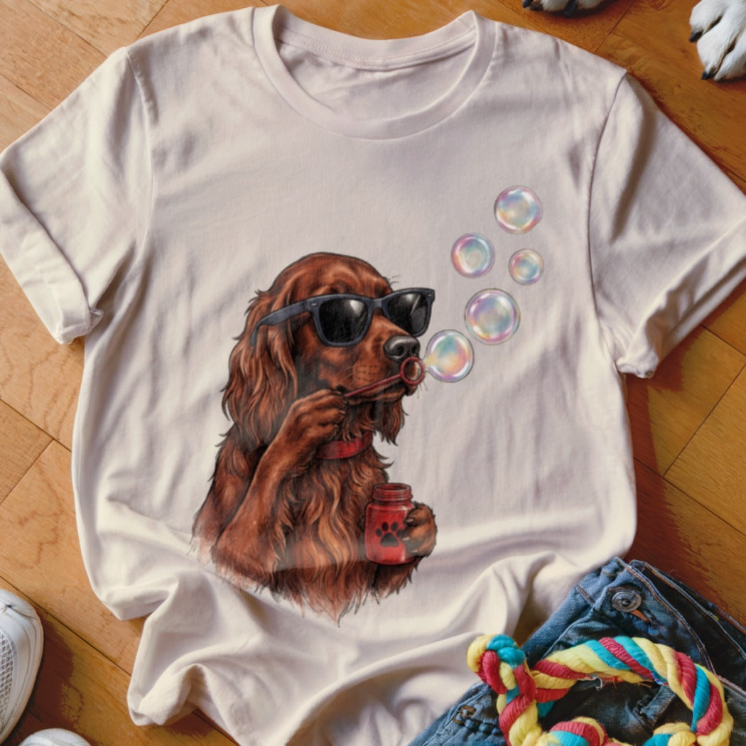 A light-colored t-shirt featuring a graphic of a brown dog wearing sunglasses and blowing bubbles.