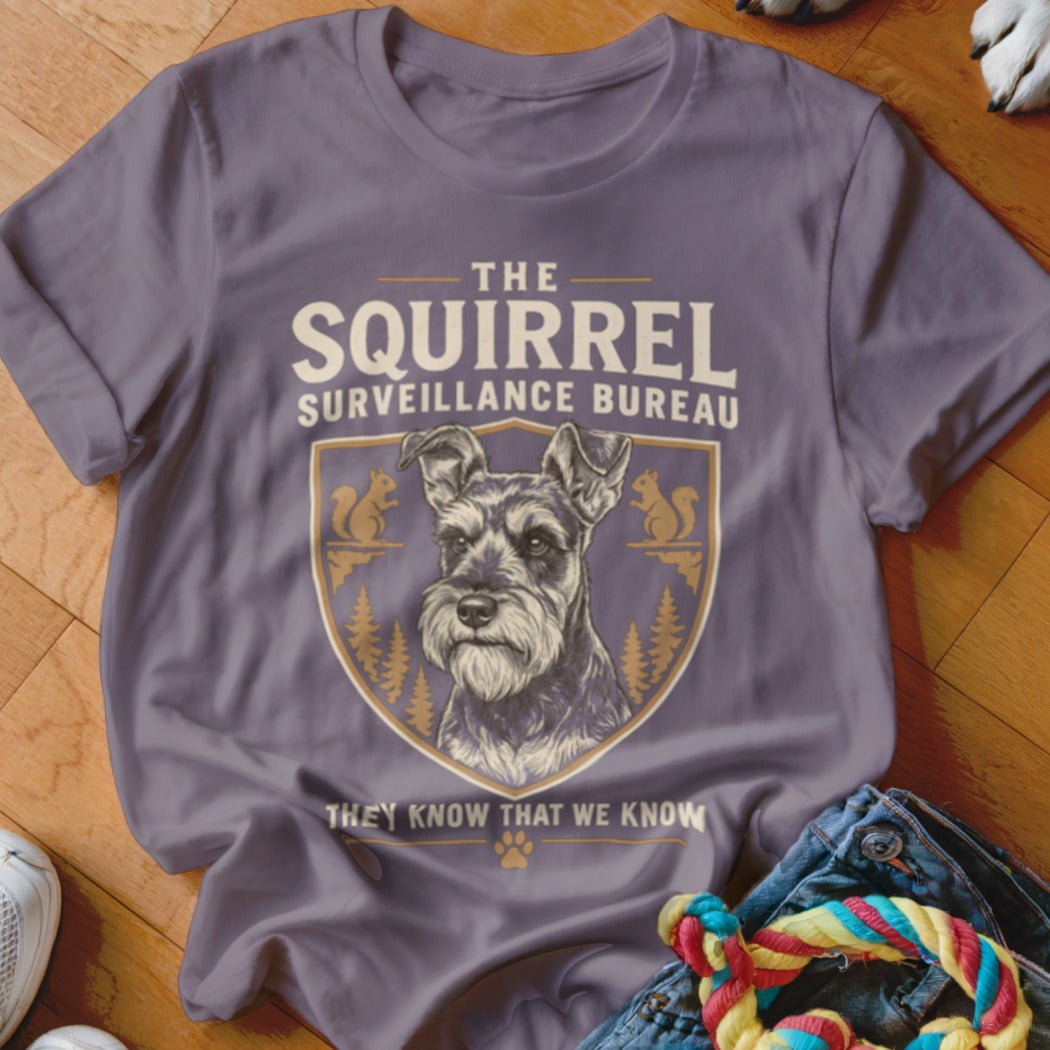 A purple t-shirt featuring a Schnauzer graphic and text that reads The Squirrel Surveillance Bureau.