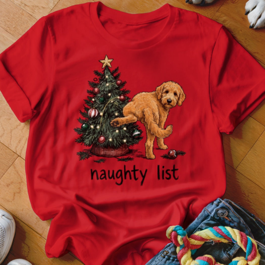 Red t-shirt with a goldendoodle standing by a Christmas tree, text says "naughty list".
