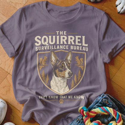 A purple t-shirt featuring a graphic crest of a dog and the text The Squirrel Surveillance Bureau.