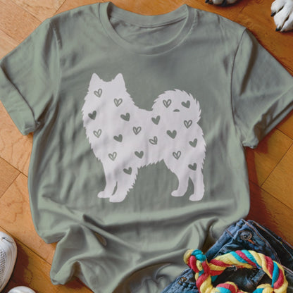 Sage green t-shirt with a white silhouette of a fluffy dog covered in small grey hearts.