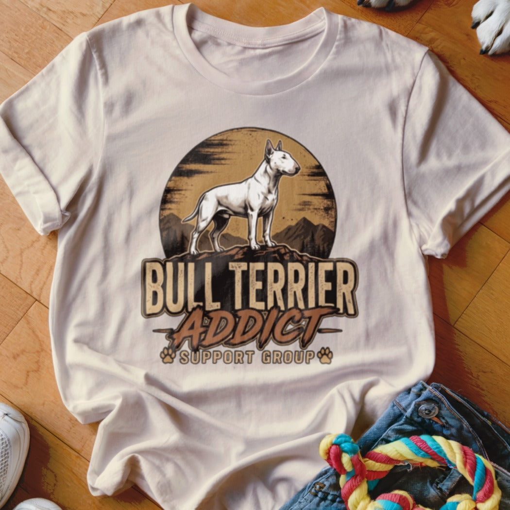A light beige t-shirt featuring a graphic of a bull terrier standing atop a mountain with the text Bull Terrier Addict Support Group.