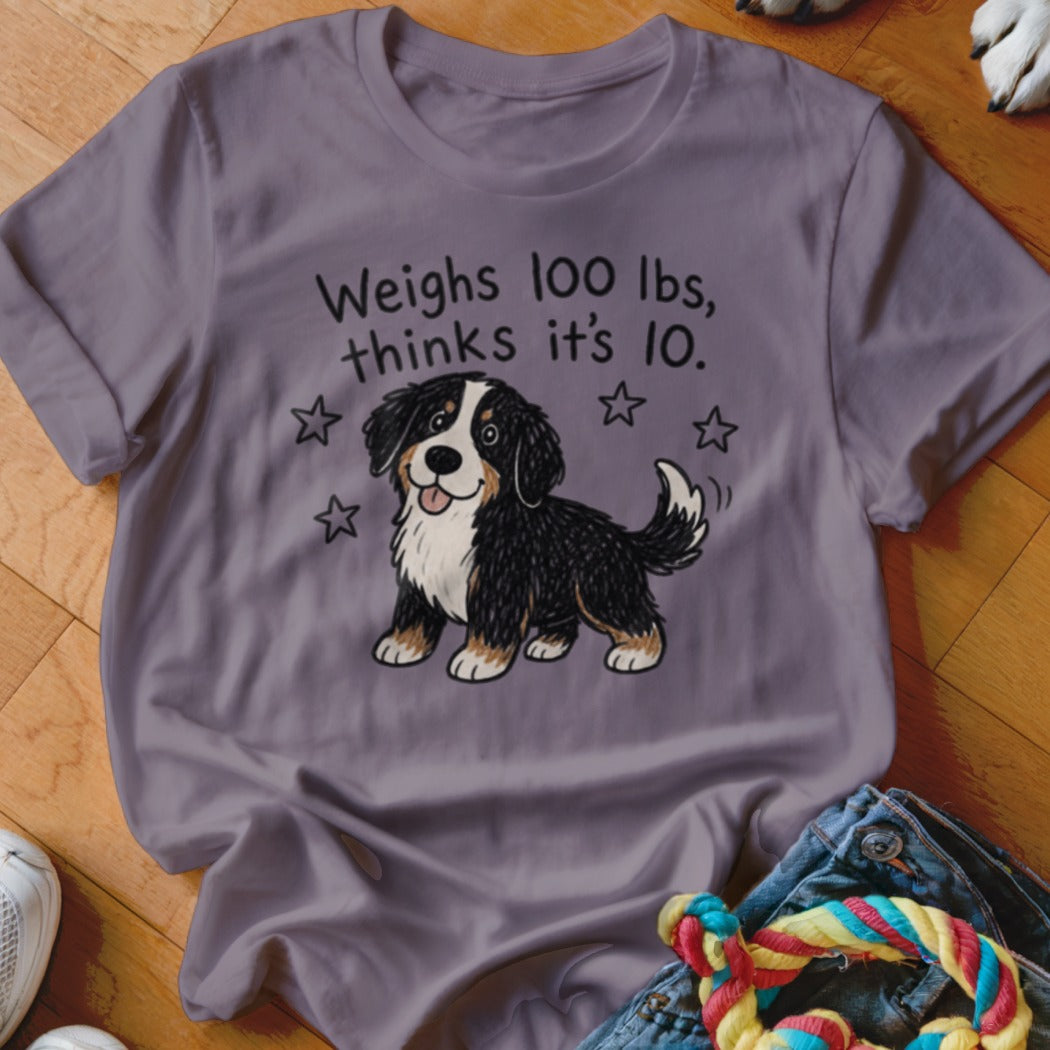 Purple t-shirt with a cartoon Bernese Mountain Dog and text "Weighs 100 lbs, thinks it's 10."