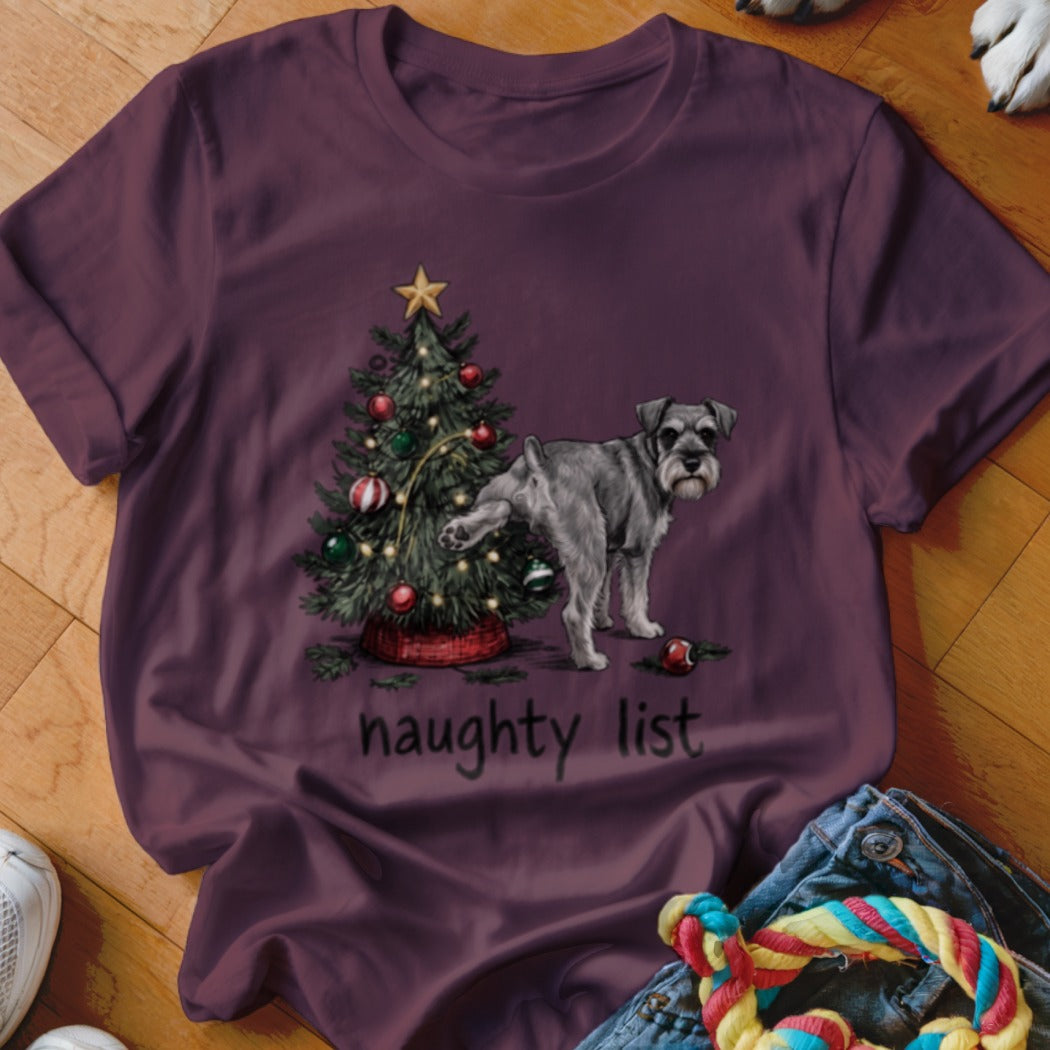 A dark purple t-shirt features a graphic of a Schnauzer lifting its leg on a Christmas tree with the text naughty list.