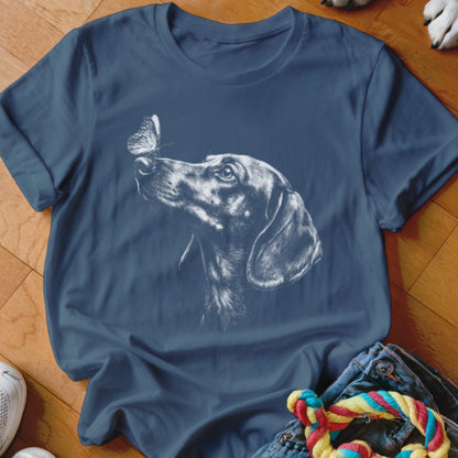 A dark blue short-sleeved t-shirt featuring a white sketch of a dachshund looking at a butterfly.