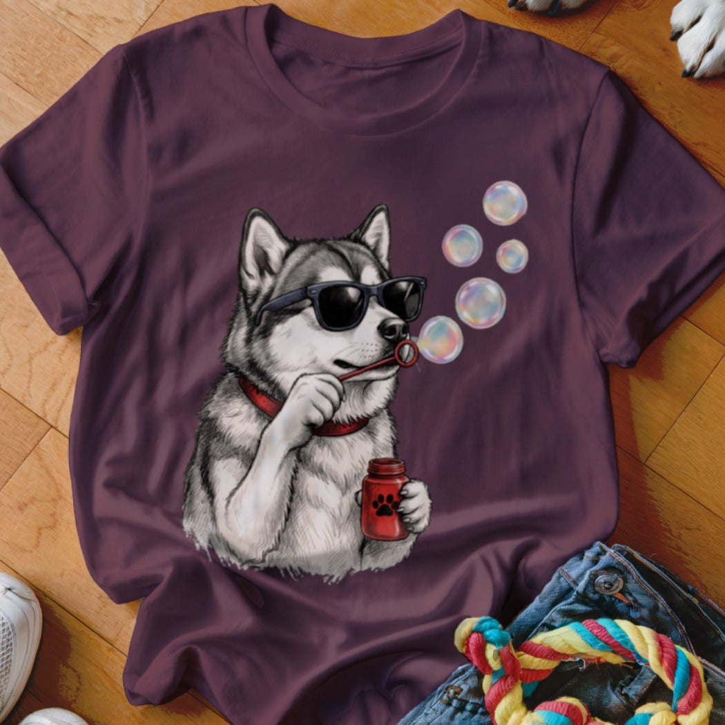 A purple t-shirt featuring a graphic of a husky wearing sunglasses and blowing soap bubbles.