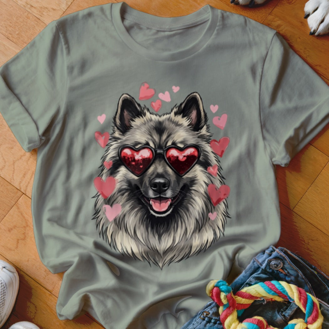 Sage green t-shirt featuring a graphic of a smiling Keeshond wearing heart-shaped sunglasses surrounded by pink hearts.