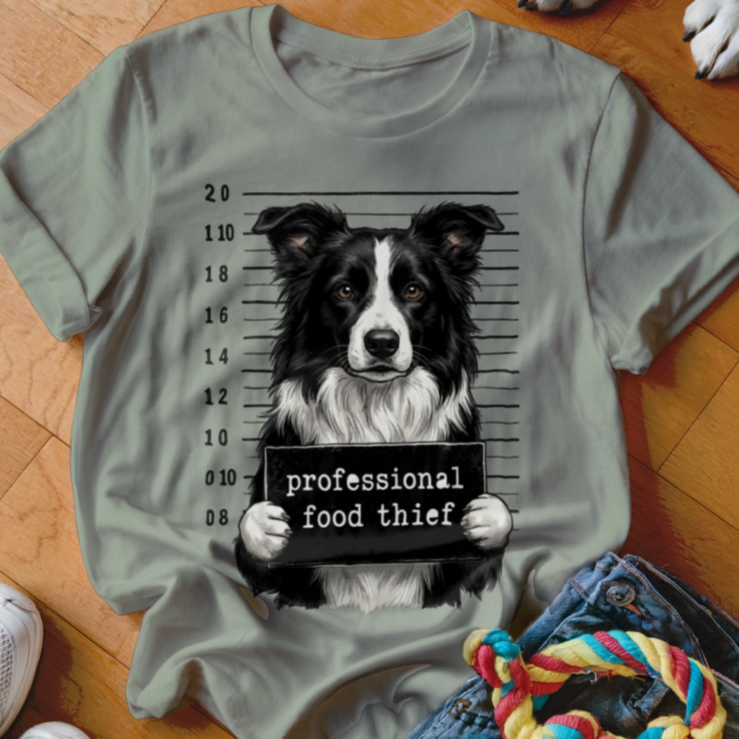 Border collie mugshot with "professional food thief" sign on shirt.