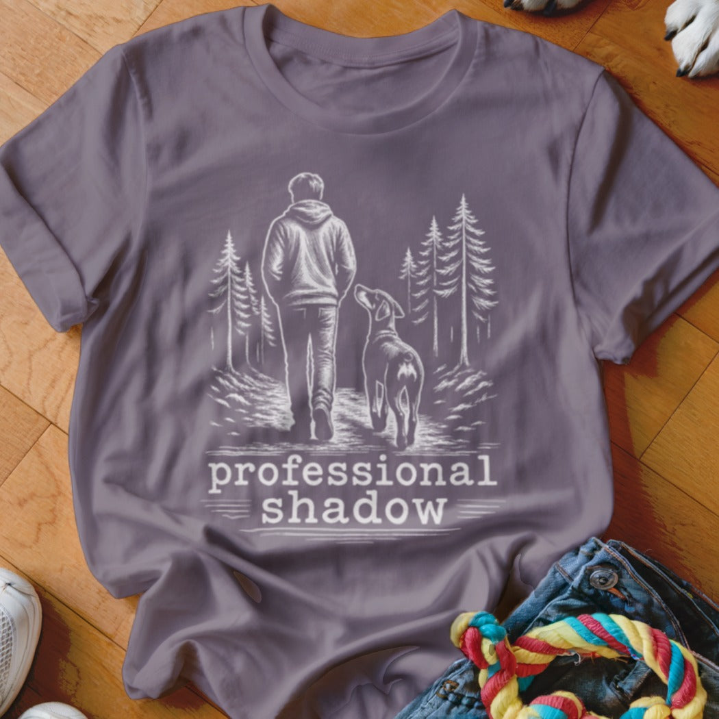 Gray t-shirt with a sketch of a person and dog walking on a path, text reads "professional shadow".