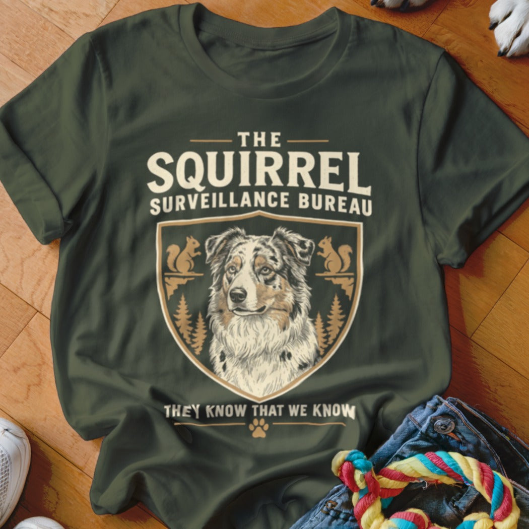 Dark green t-shirt with a graphic of a dog, squirrels, and text reading The Squirrel Surveillance Bureau.