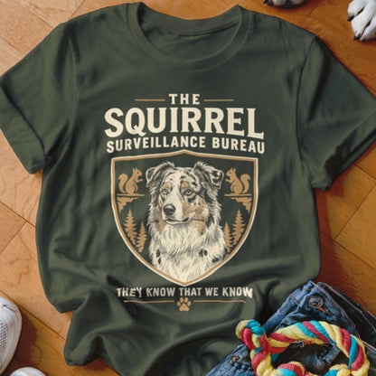 Dark green t-shirt with a graphic of a dog, squirrels, and text reading The Squirrel Surveillance Bureau.