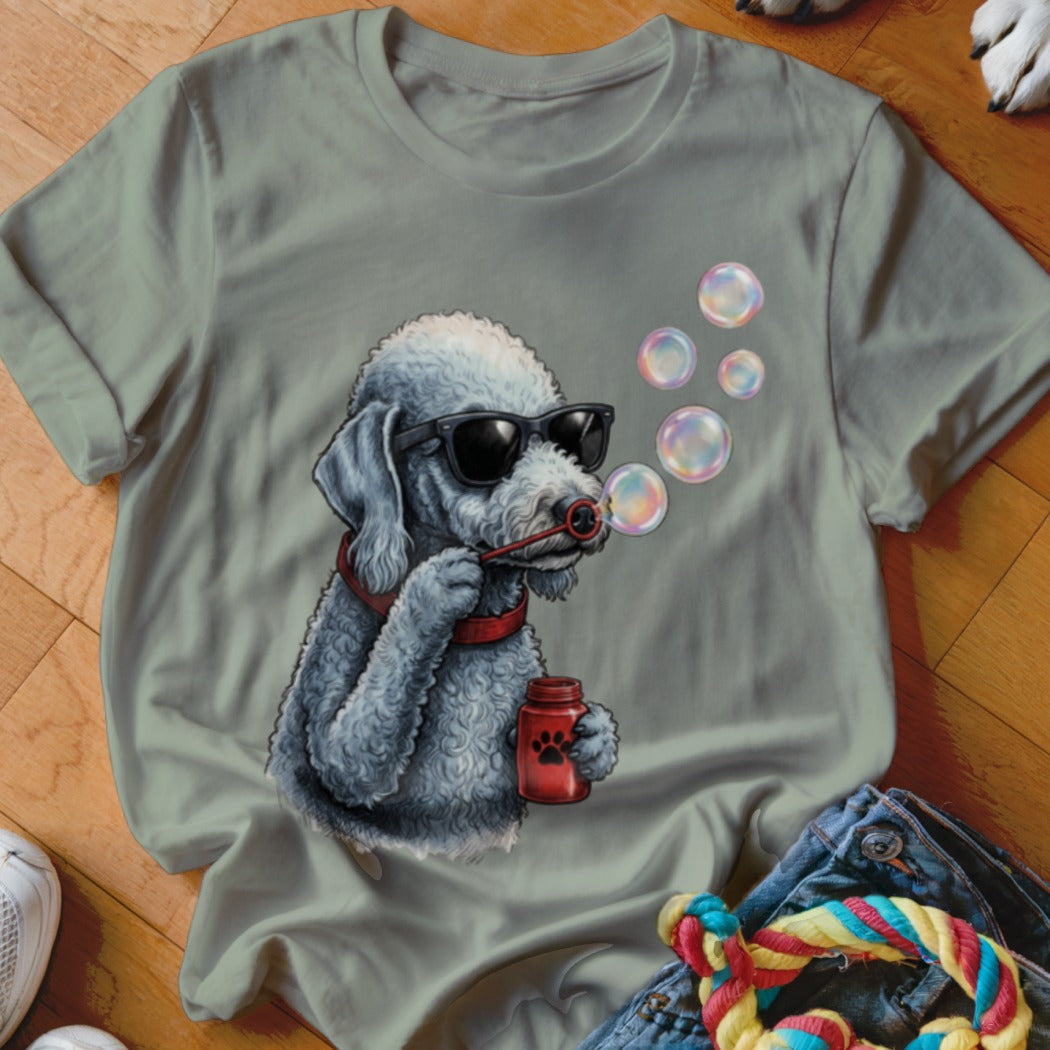 Olive green t-shirt featuring a graphic of a grey poodle wearing sunglasses and blowing bubbles.