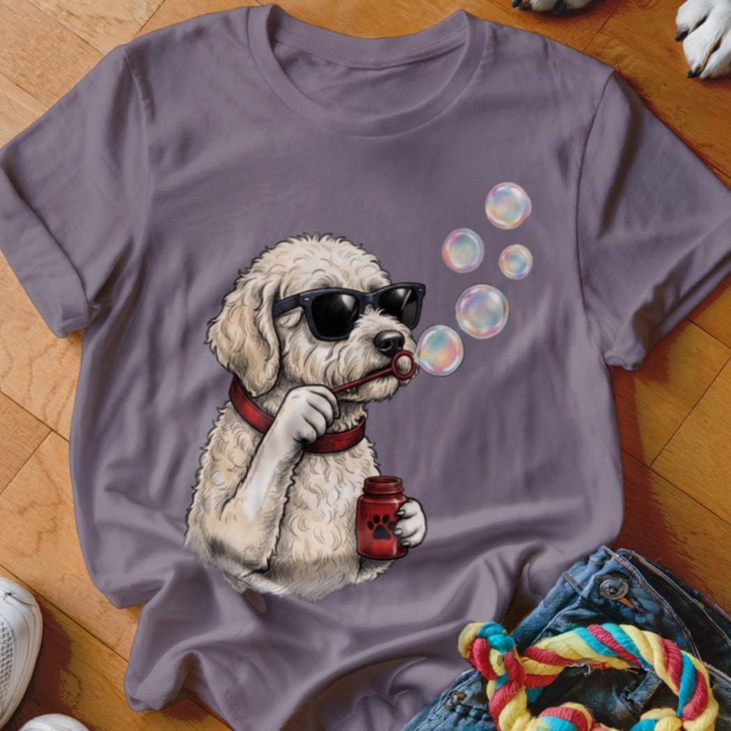 A grey crewneck t-shirt featuring a graphic of a curly white dog wearing sunglasses and blowing bubbles.