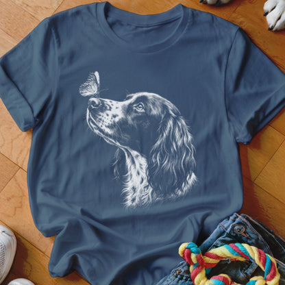 A blue t-shirt printed with a white line art graphic of a dog looking at a butterfly.