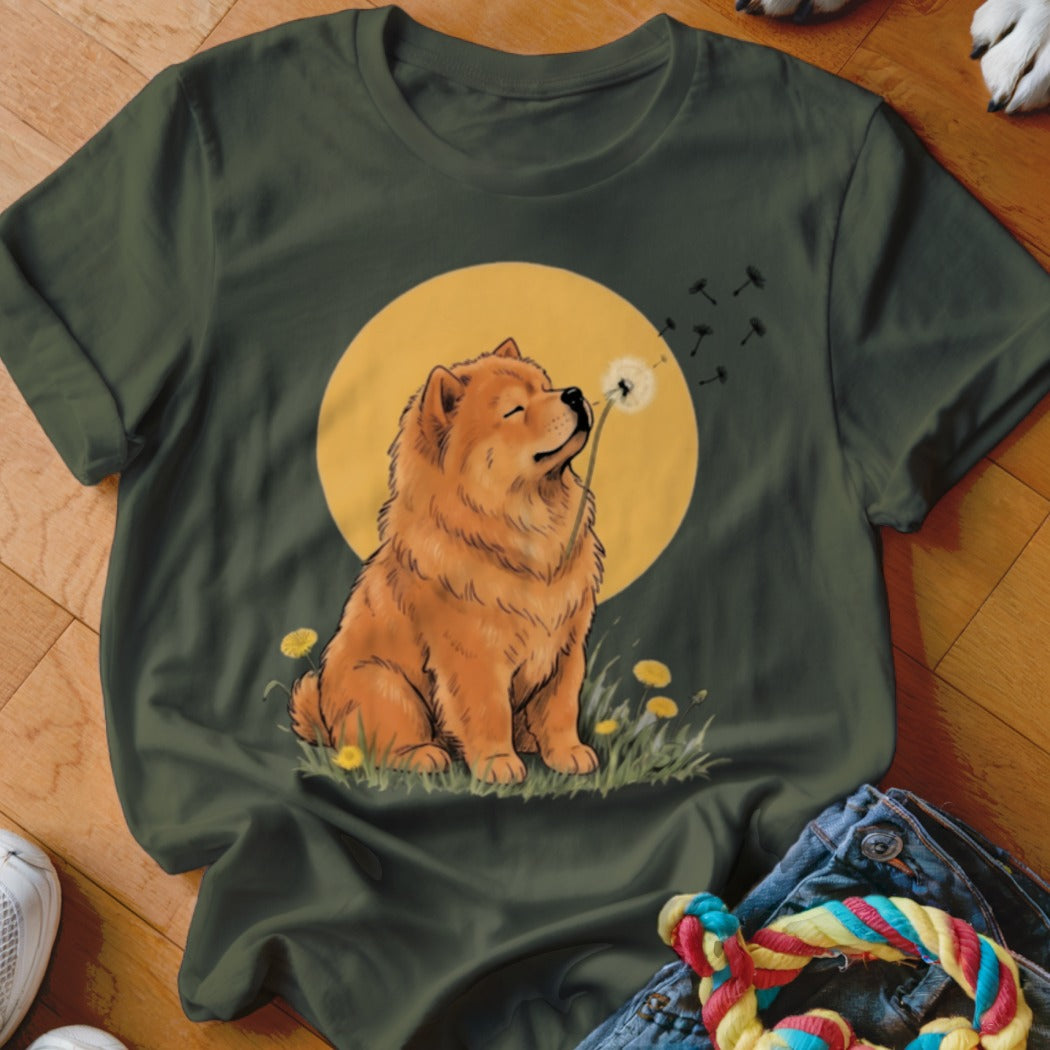 Dark green t-shirt with a graphic of a fluffy orange dog blowing a dandelion seed head against a yellow moon.