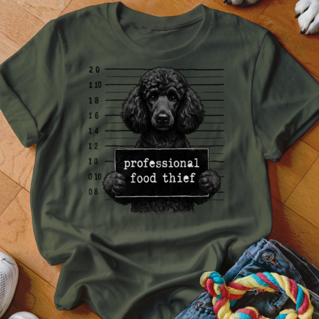 Black poodle mugshot on olive green t-shirt reads "professional food thief".