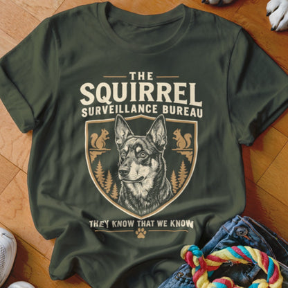 Dark green t-shirt featuring a dog graphic, squirrel illustrations, and text reading The Squirrel Surveillance Bureau.