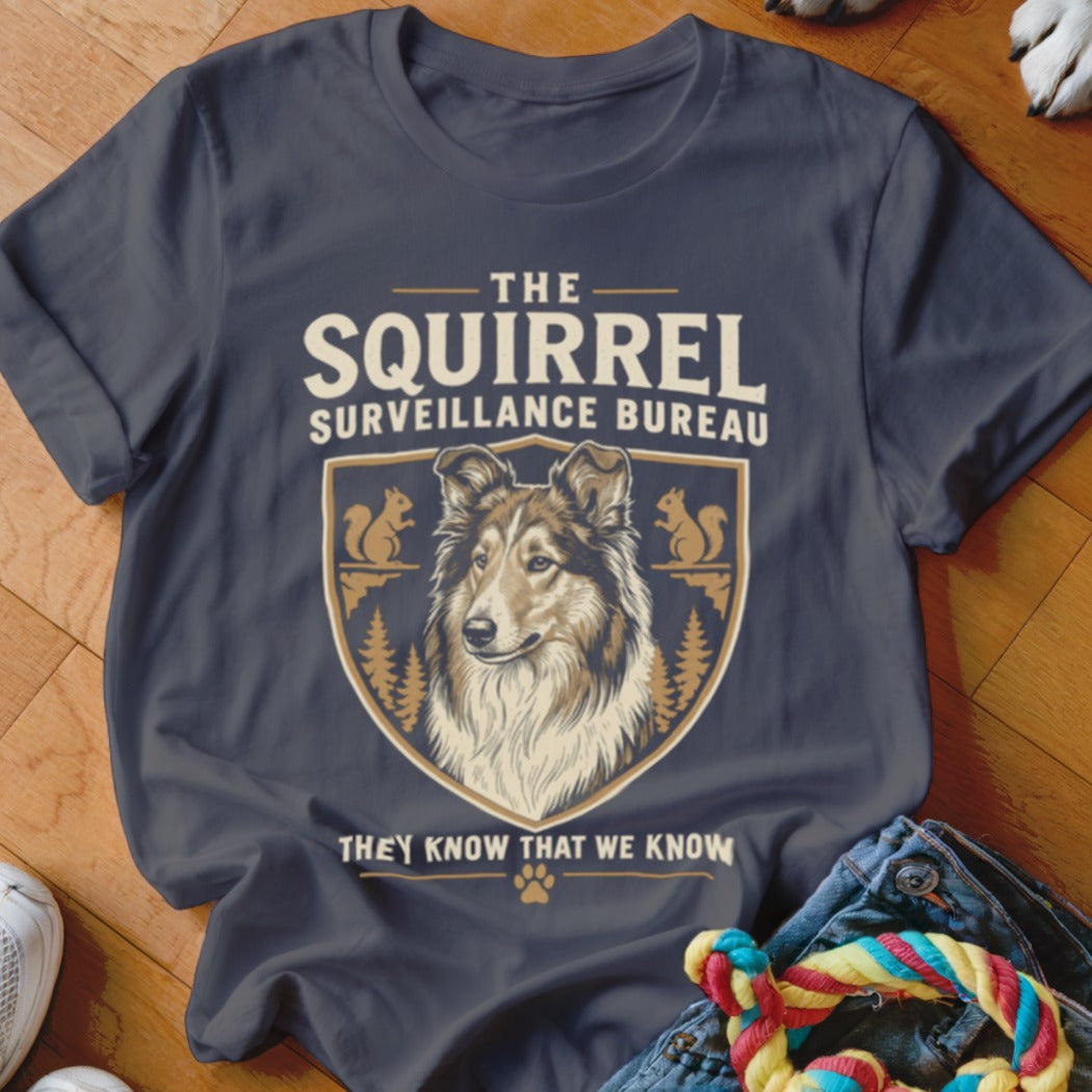 Dark gray t-shirt with a vintage-style graphic featuring a collie and squirrels, with text reading The Squirrel Surveillance Bureau.