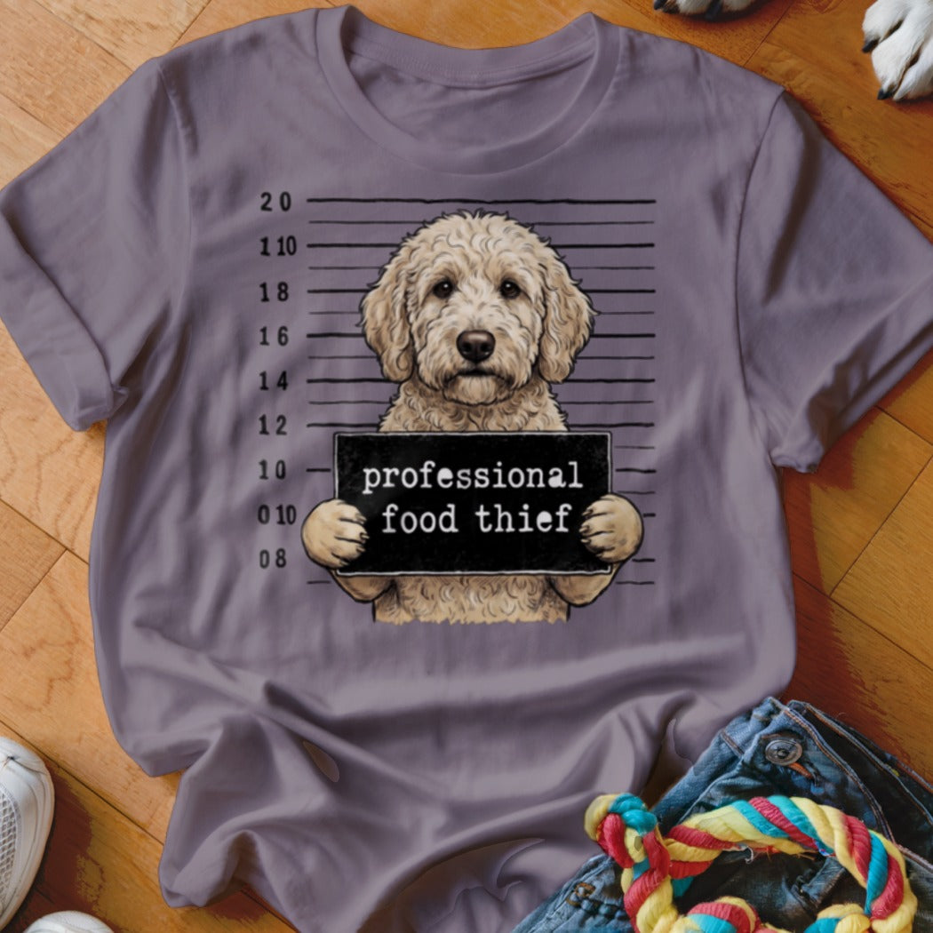 Goldendoodle dog mugshot with "professional food thief" sign.