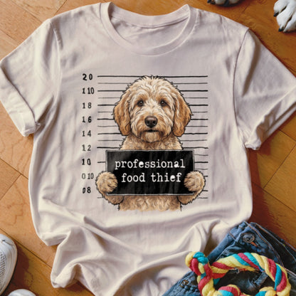 Goldendoodle dog in mugshot pose holding a sign that reads "professional food thief".