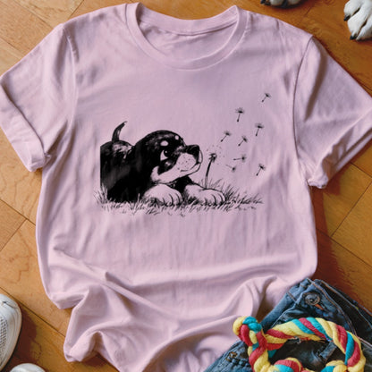 Light pink crewneck t-shirt featuring a black and white sketch of a puppy blowing dandelion seeds.