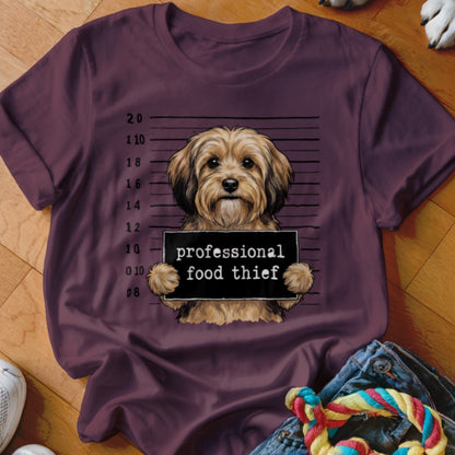 Mugshot of a fluffy dog holding a sign that says "professional food thief".