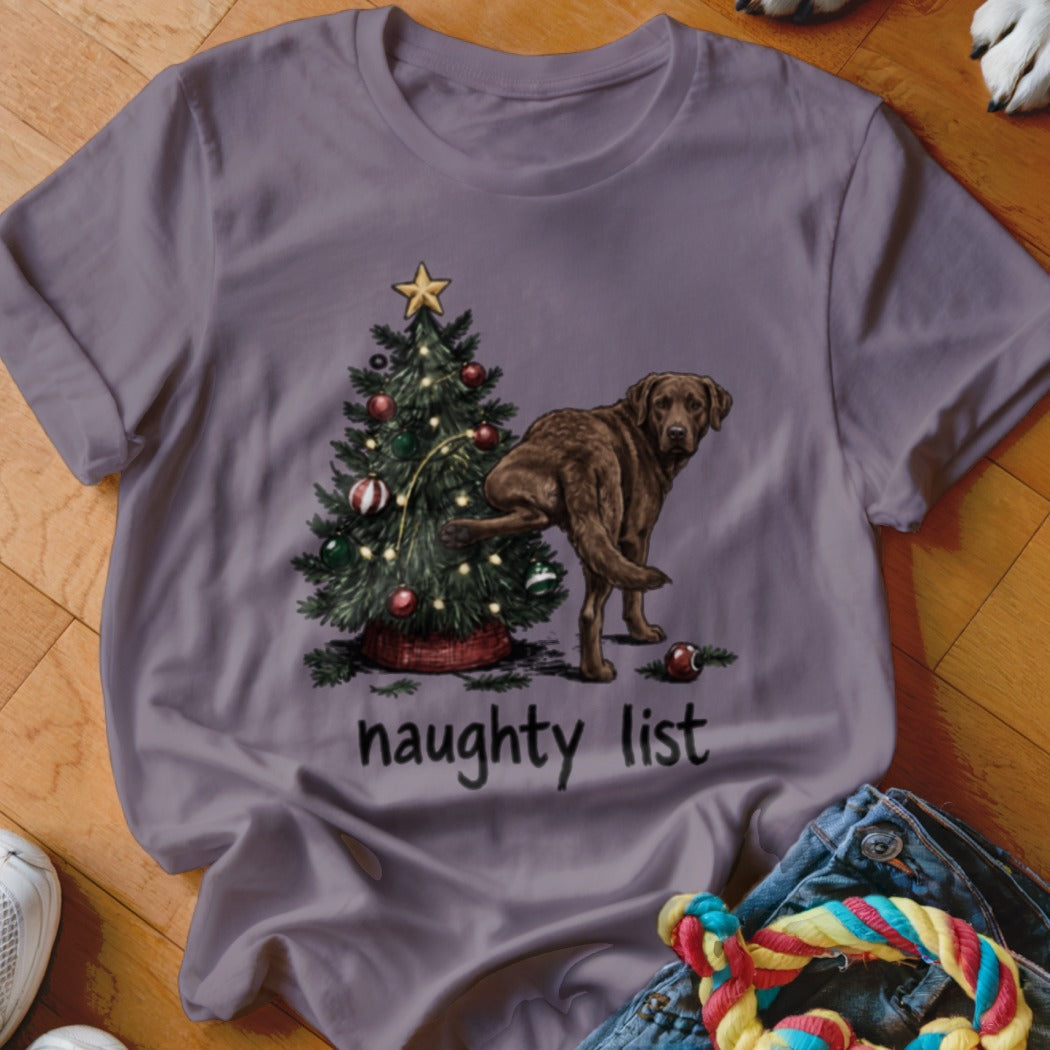Brown dog lifting leg next to Christmas tree with text "naughty list."