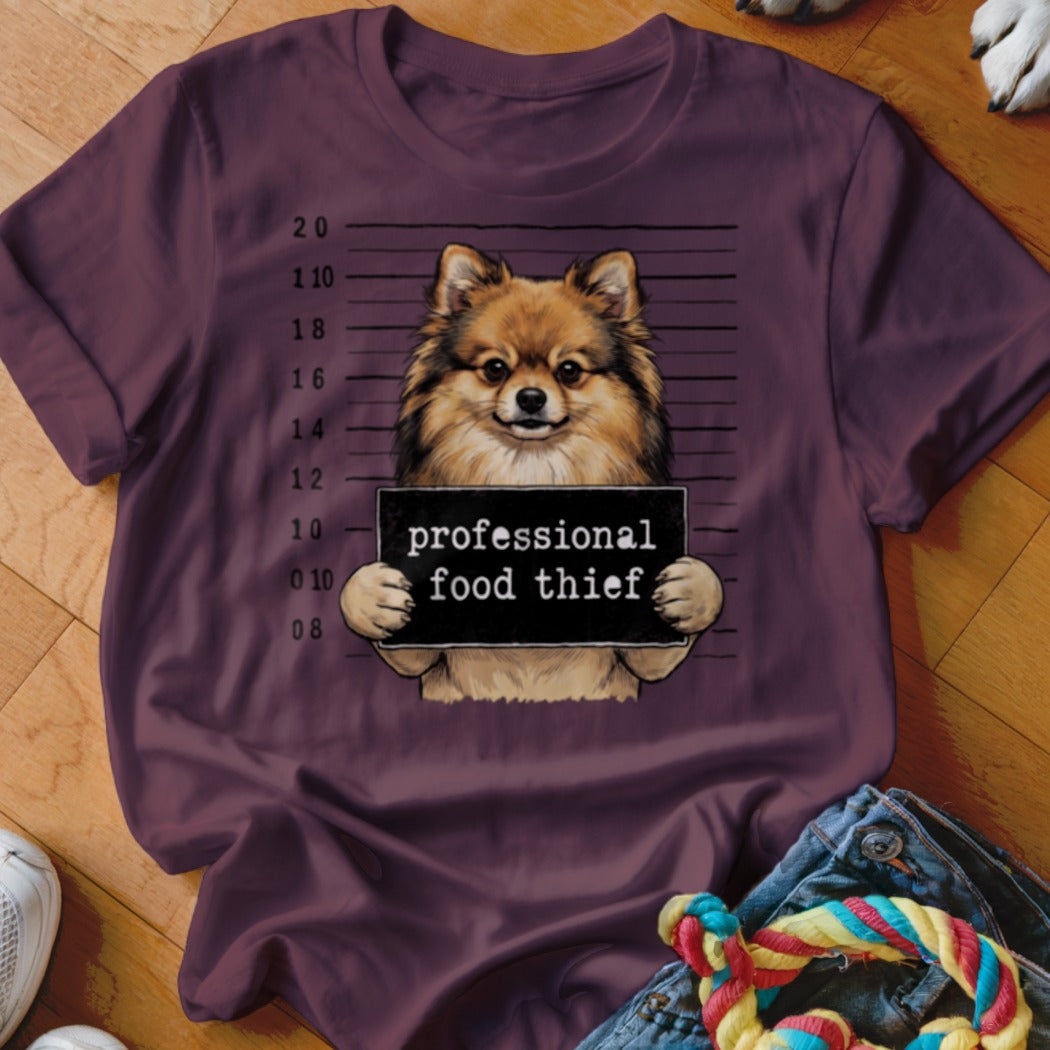 Pomeranian dog mugshot holding sign that says "professional food thief".