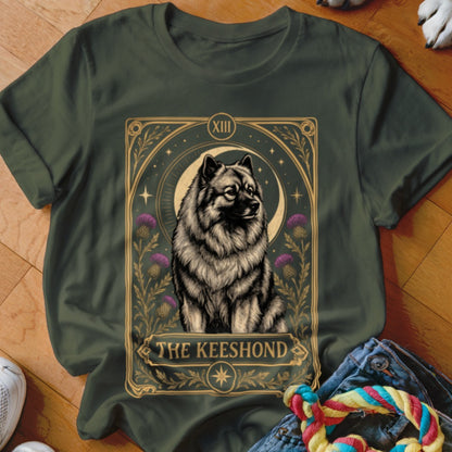 A dark green t-shirt featuring a tarot-style graphic of a Keeshond dog and purple flowers.