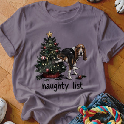 Basset hound marking a Christmas tree with text "naughty list" on shirt.