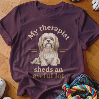 Burgundy t-shirt with a fluffy white dog and text "My therapist sheds an awful lot."