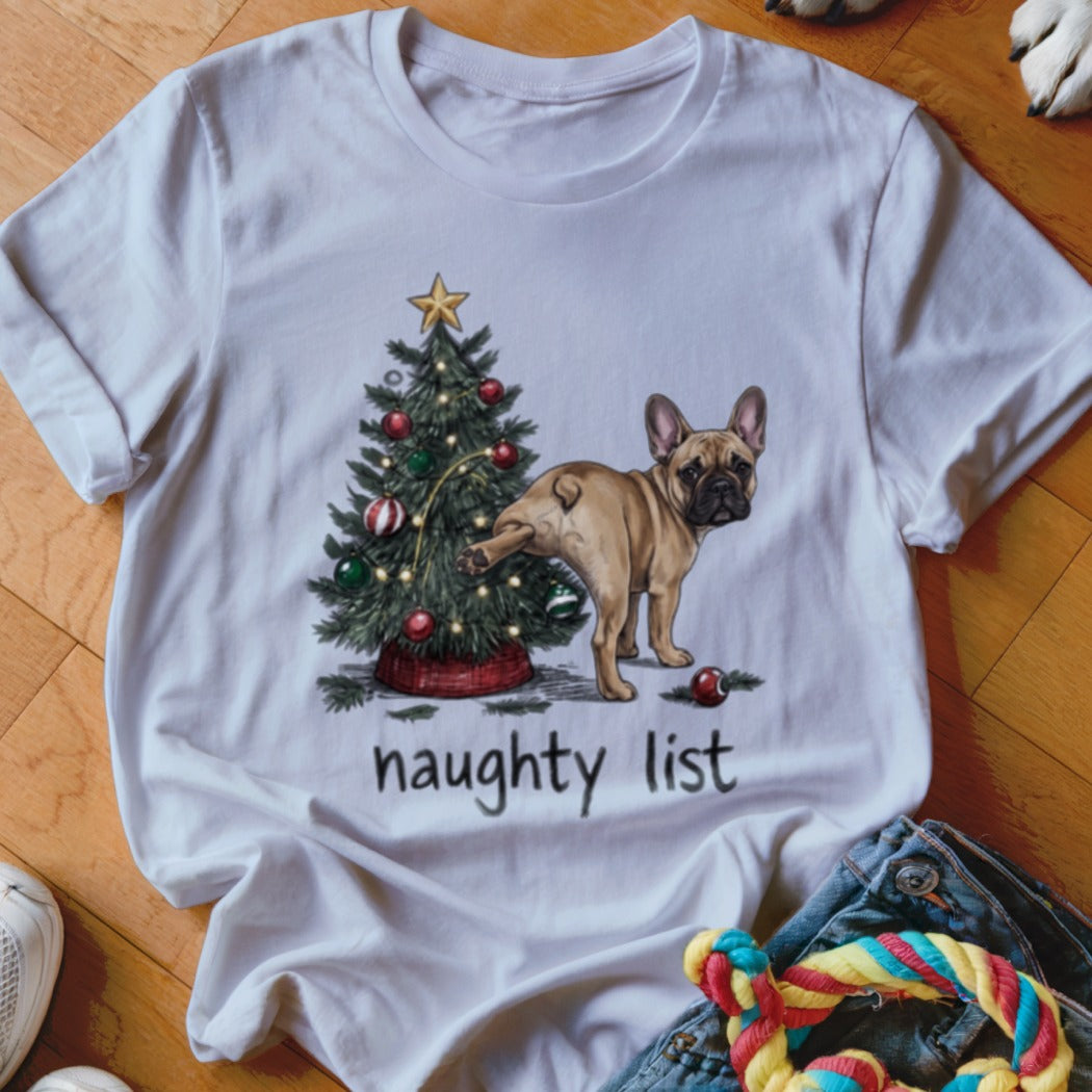 A white crewneck t-shirt featuring an illustration of a French Bulldog lifting its leg next to a decorated Christmas tree, with the text naughty list underneath.