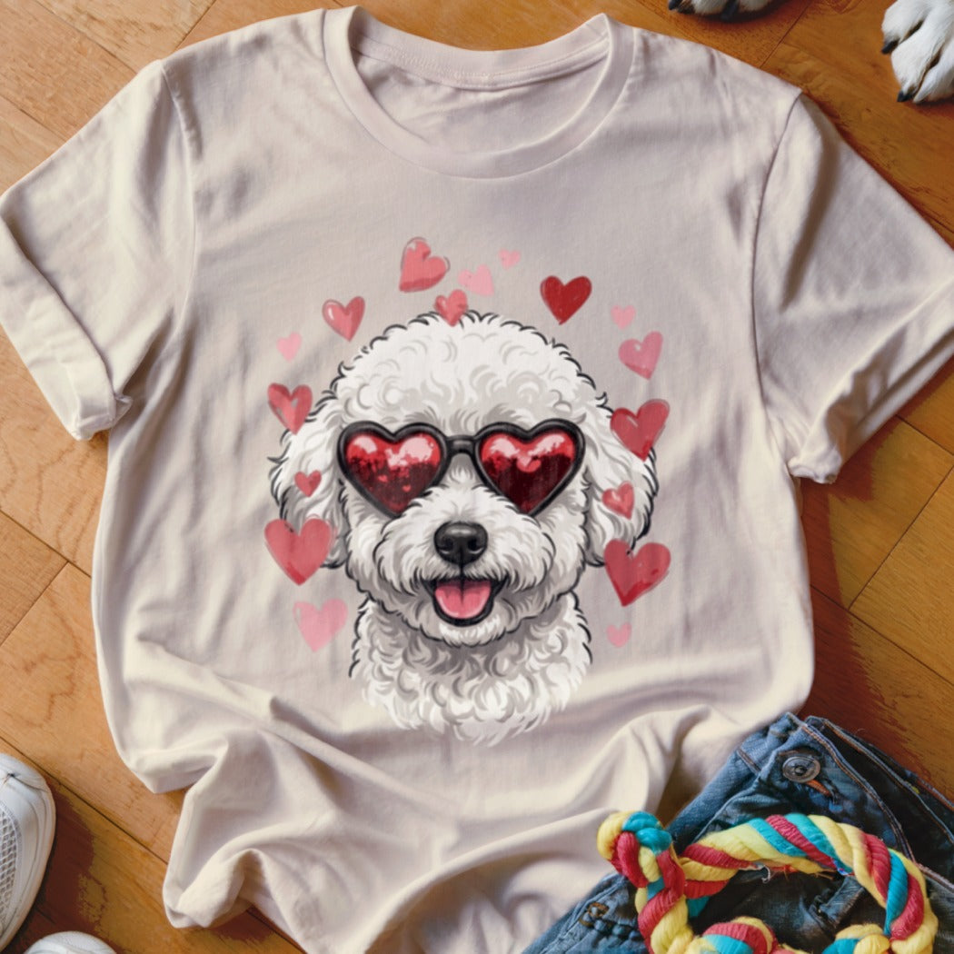 Light beige t-shirt featuring a graphic of a white fluffy dog wearing heart-shaped sunglasses, surrounded by pink hearts.