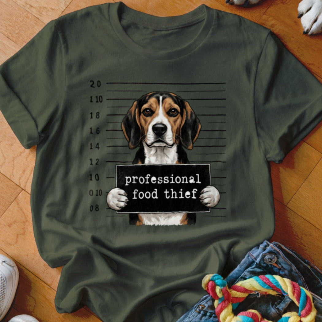 Beagle dog mugshot with "professional food thief" sign on a green t-shirt.