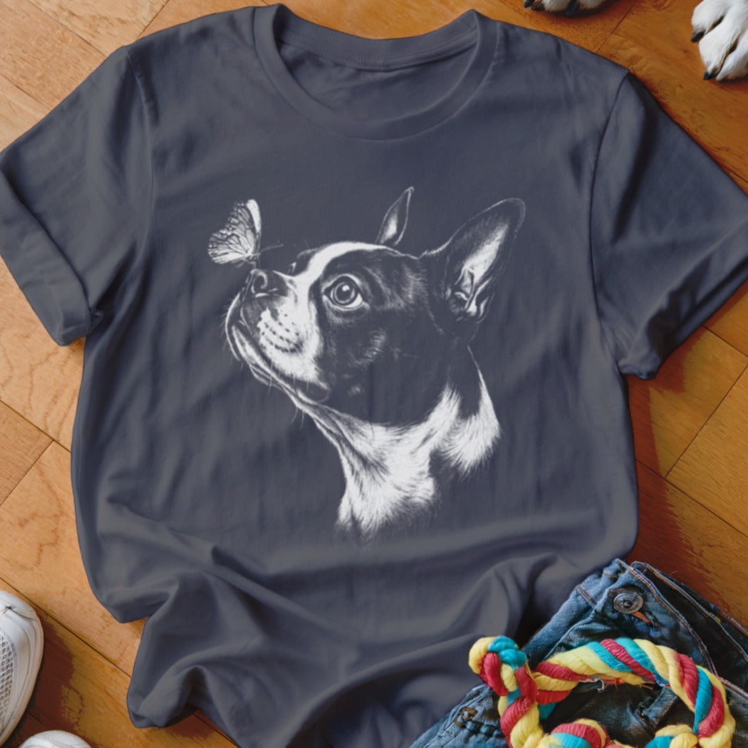 A dark gray t-shirt featuring a white sketch graphic of a Boston Terrier looking at a butterfly on its nose.