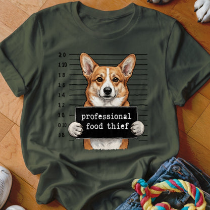 Corgi with mugshot sign reading "professional food thief" on olive green t-shirt.