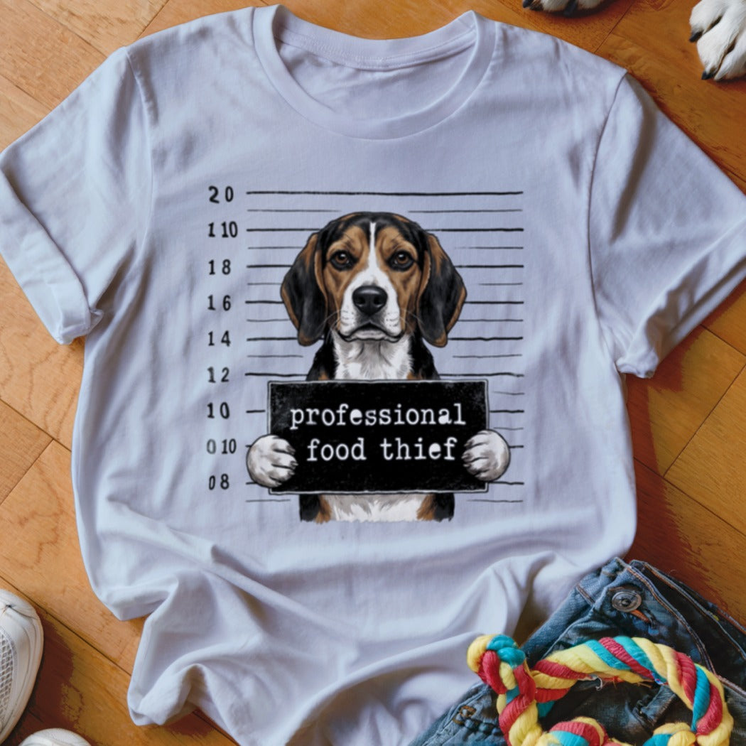 Beagle dog mugshot with "professional food thief" sign.