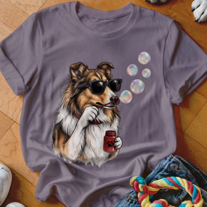 A purple t-shirt featuring a graphic of a Sheltie dog wearing sunglasses and blowing bubbles.