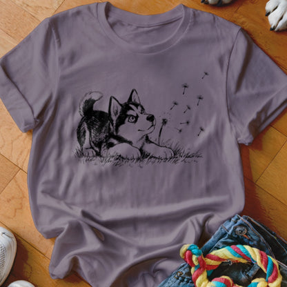 A purple crewneck t-shirt featuring a black graphic of a puppy playing with dandelions.