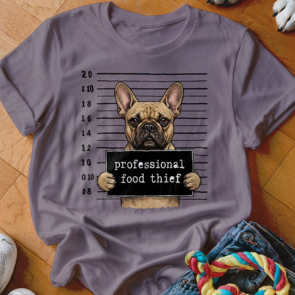 French bulldog mugshot with "professional food thief" sign on grey t-shirt.