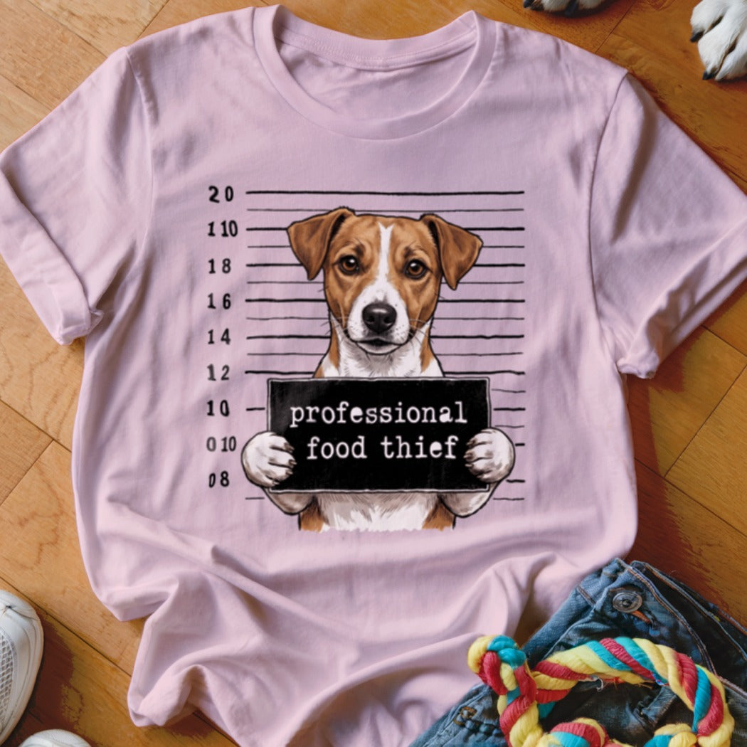 Dog mugshot graphic with text "professional food thief" on pink t-shirt.