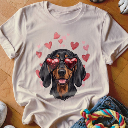 Light beige t-shirt featuring a graphic of a black and tan dachshund wearing heart sunglasses surrounded by floating red hearts.