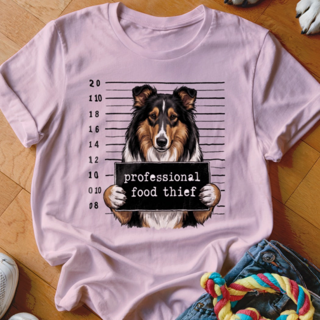 Sheltie dog in mugshot holding sign that says "professional food thief"